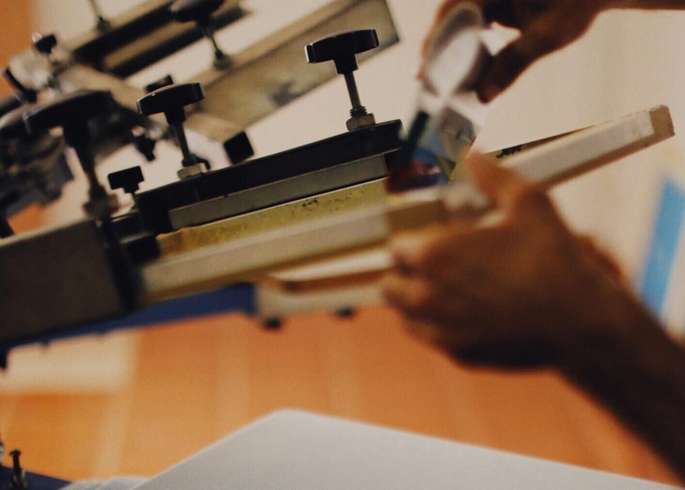 Close-up of a man using a T-shirt printing machine indoors.